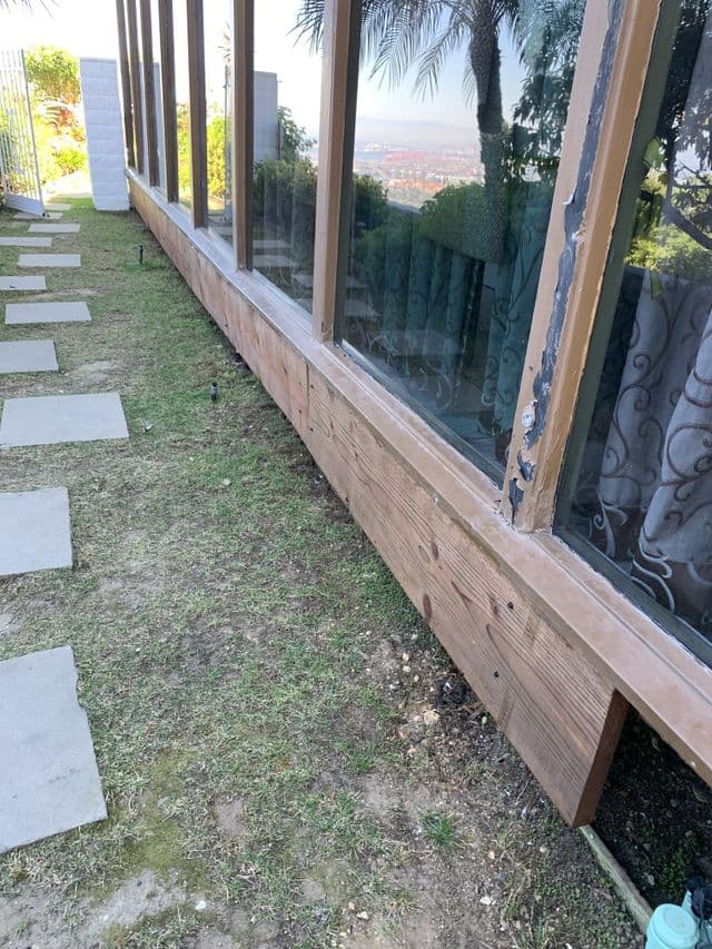 Glass wall in a wood frame running along a walkway above a hillside view. Work by Construction Hub in Los Angeles.