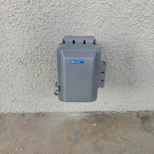 Weatherproof in-use cover over GFCI outlet on stucco wall. Work by Construction Hub in Los Angeles.