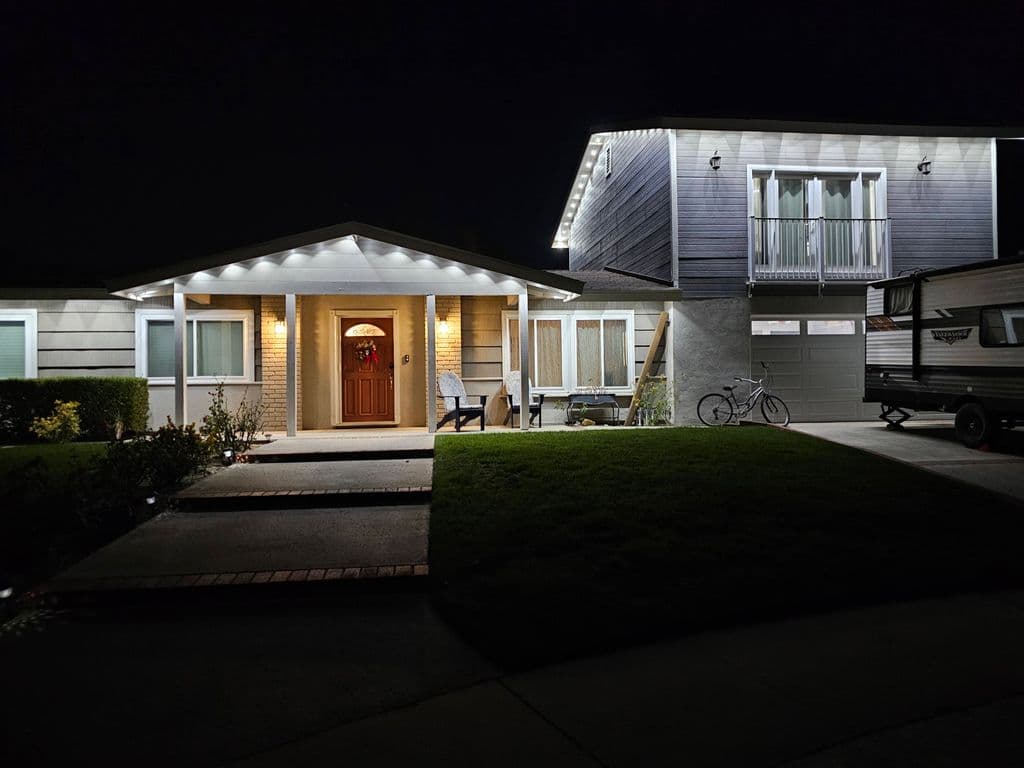 Permanent white roofline lights outlining house eaves at night. Work by Construction Hub in Los Angeles.