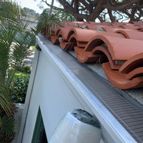Mesh gutter guard installed along clay tile roof edge. Work by Construction Hub in Los Angeles.