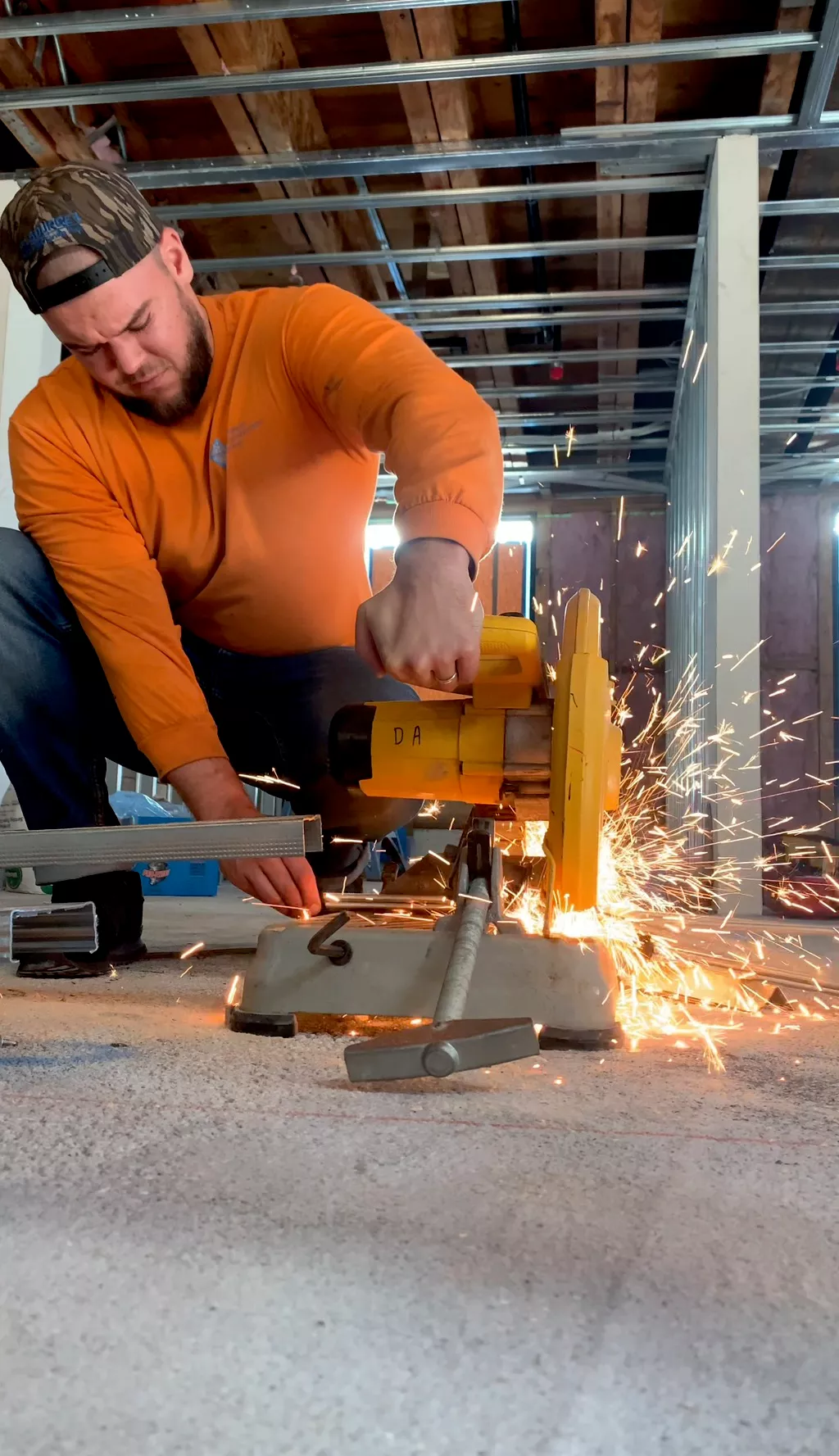 Construction Hub crew member cutting metal stud track with a chop saw on a job site