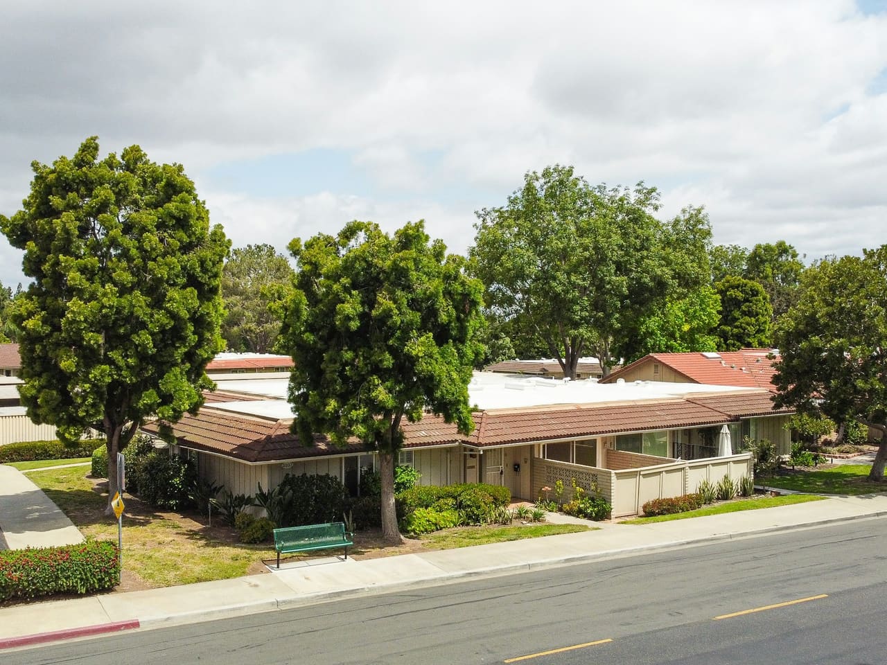 Single-story ranch homes behind trees along a flat suburban street
