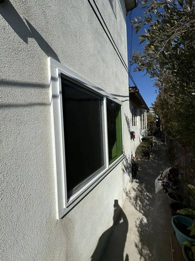 New window screen fitted in a stucco wall along a side walkway. Work by Construction Hub in Los Angeles.
