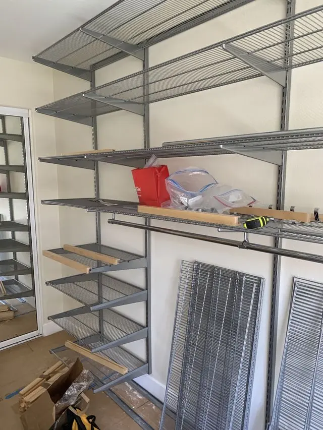 Wire shelving frames and rails installed in a closet, spare parts waiting below. Work by Construction Hub in Los Angeles.