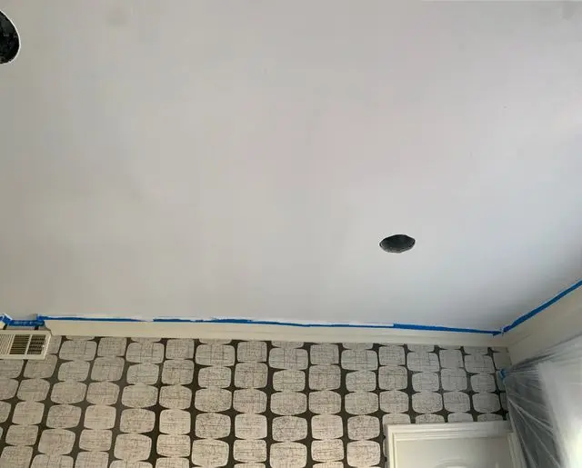 Ceiling patched smooth above a wall of textured block, blue tape along the joint. After the work, by Construction Hub in Los Angeles.