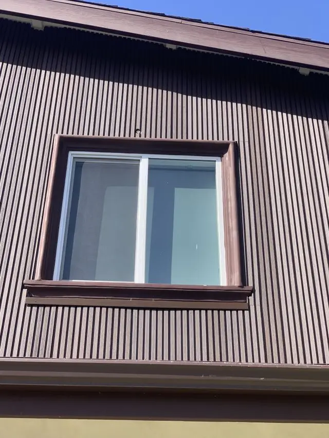 Sliding window with a new screen set into dark corrugated siding. Work by Construction Hub in Los Angeles.