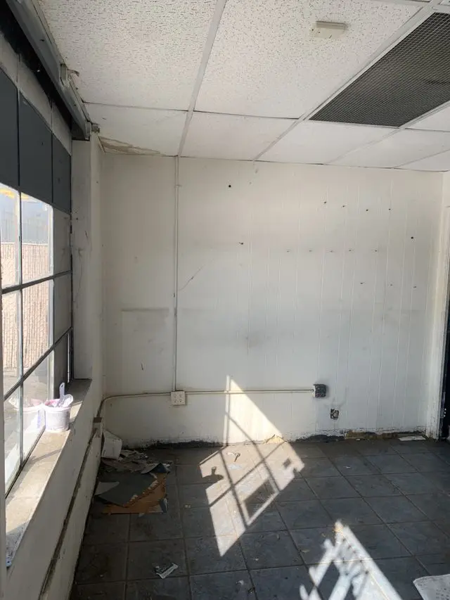 Office room with a suspended ceiling and a long wall stripped ready for patching. Work by Construction Hub in Los Angeles.