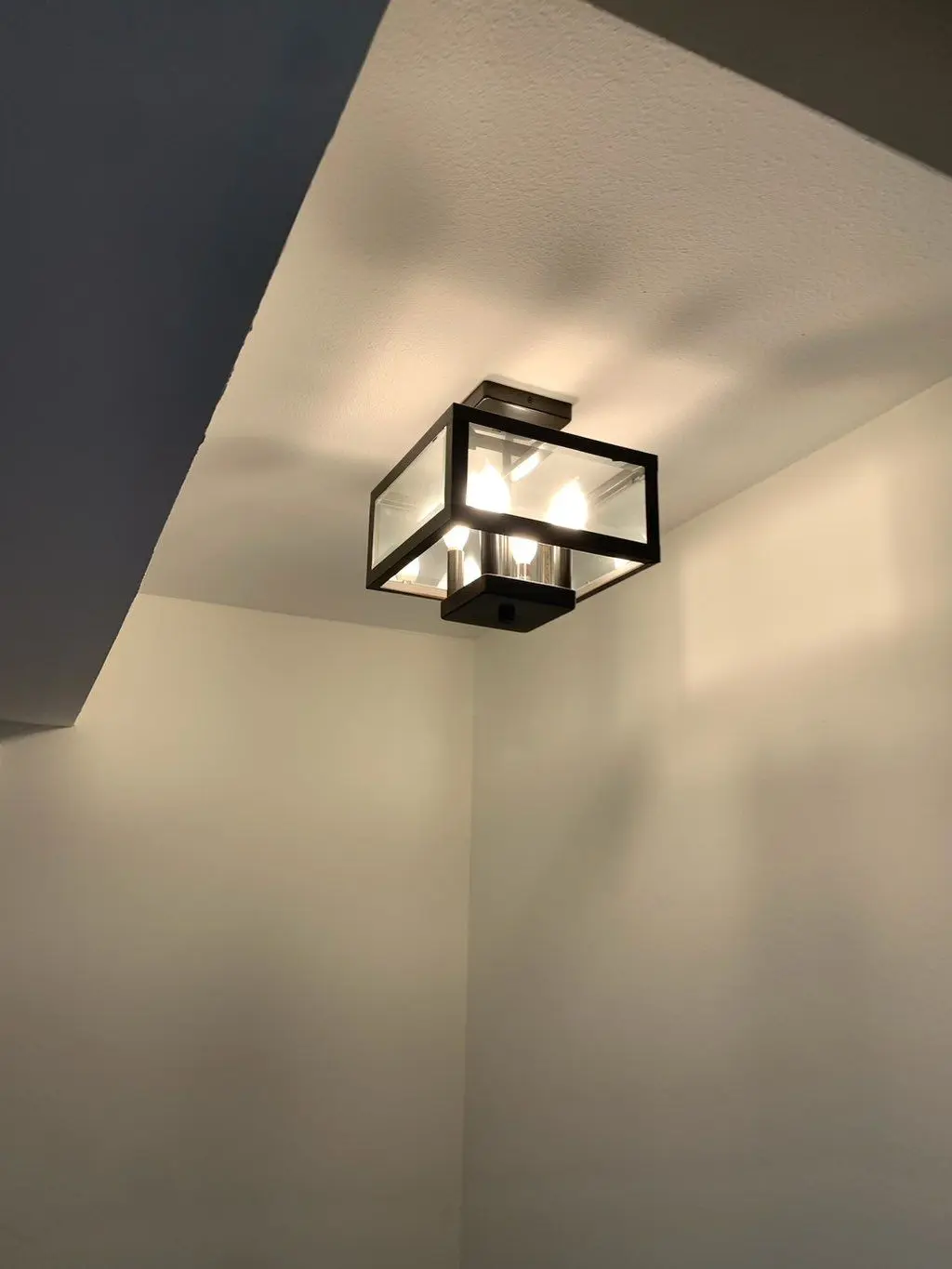 Black square flush mount glass ceiling light installed and lit. Work by Construction Hub in Los Angeles.