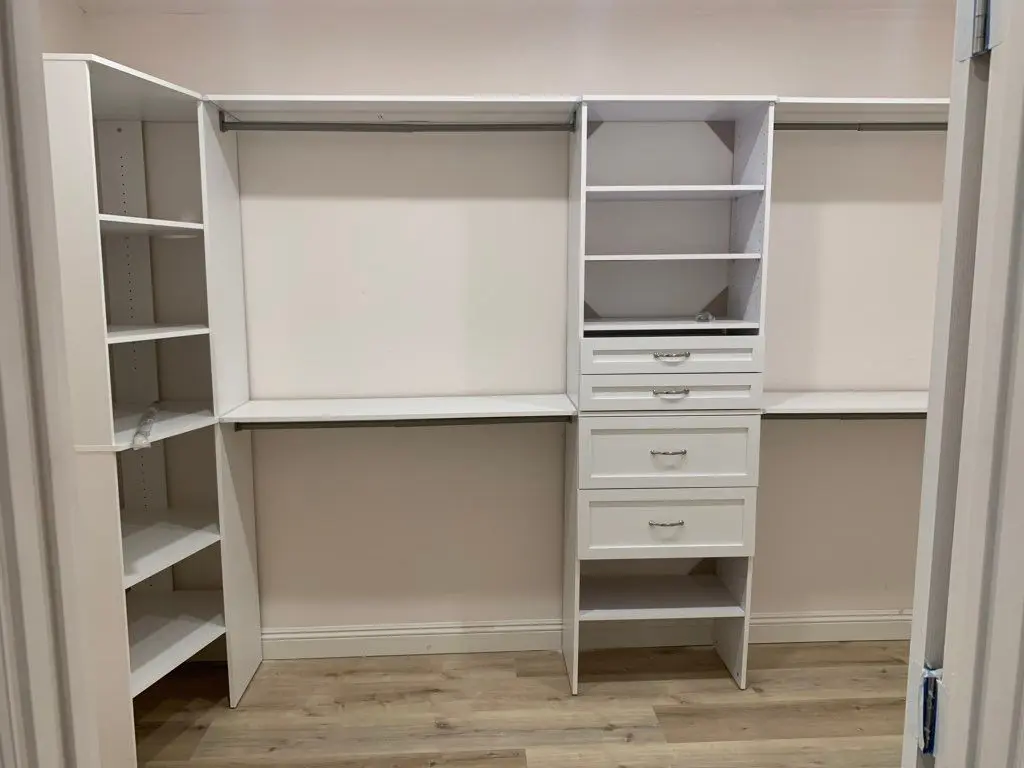 White closet organizer with shelves, drawers and hanging rods. Work by Construction Hub in Los Angeles.