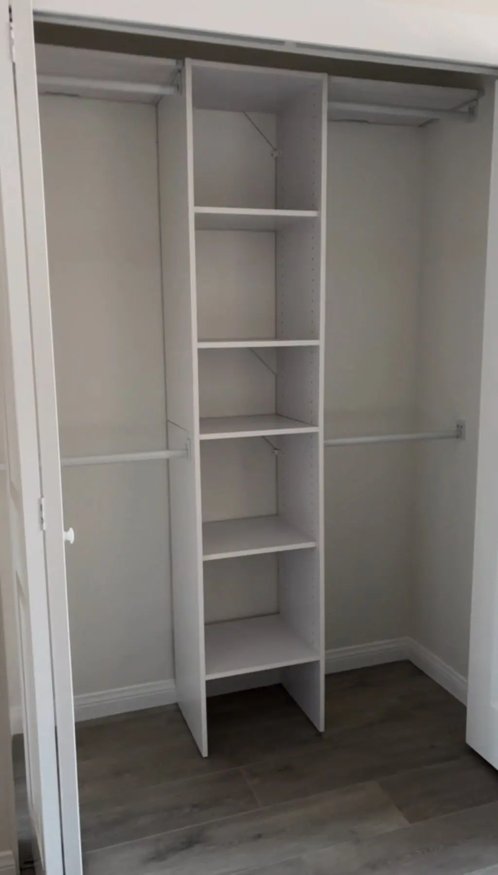 Closet organizer with center shelf tower and hanging rods. Work by Construction Hub in Los Angeles.