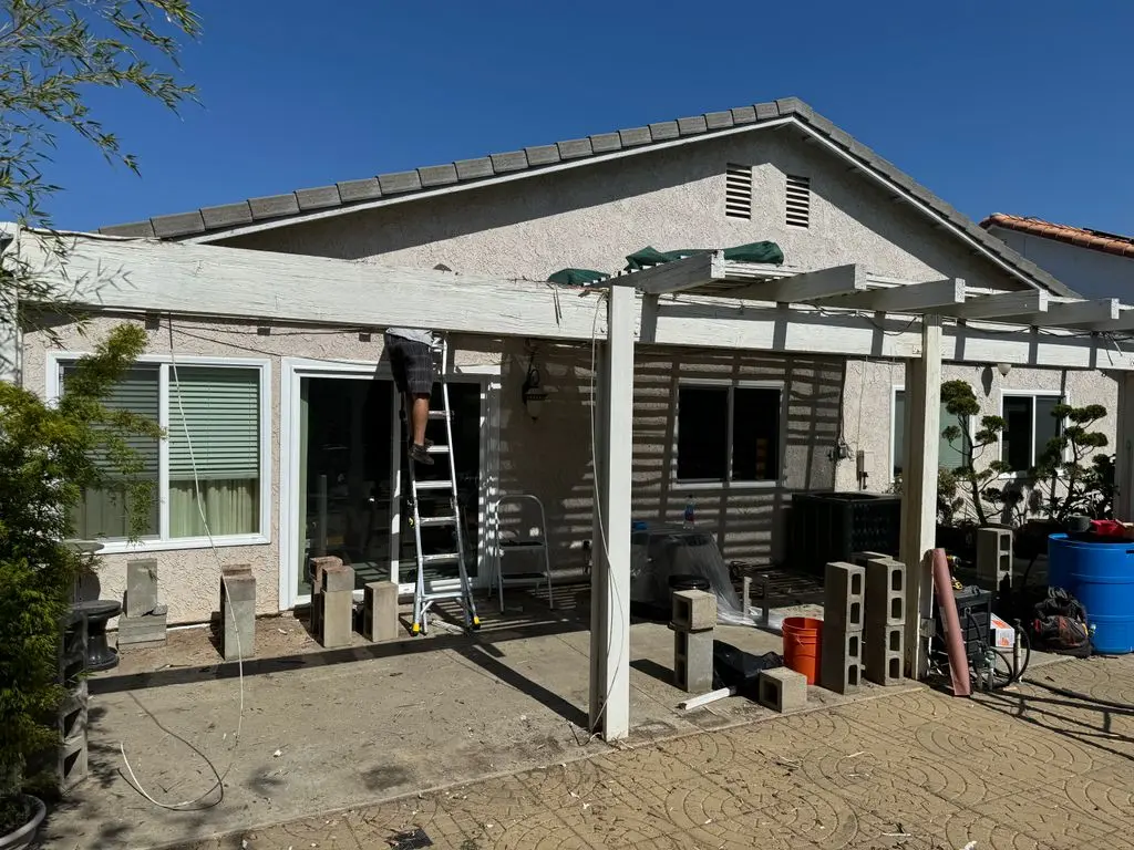 Old patio cover being dismantled with ladder and removed posts. Work by Construction Hub in Los Angeles.