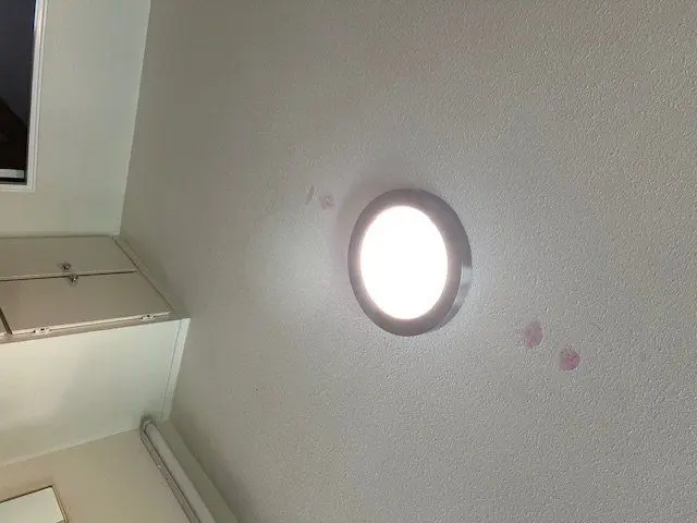 Round flush mount ceiling light lit against a textured ceiling. Work by Construction Hub in Los Angeles.