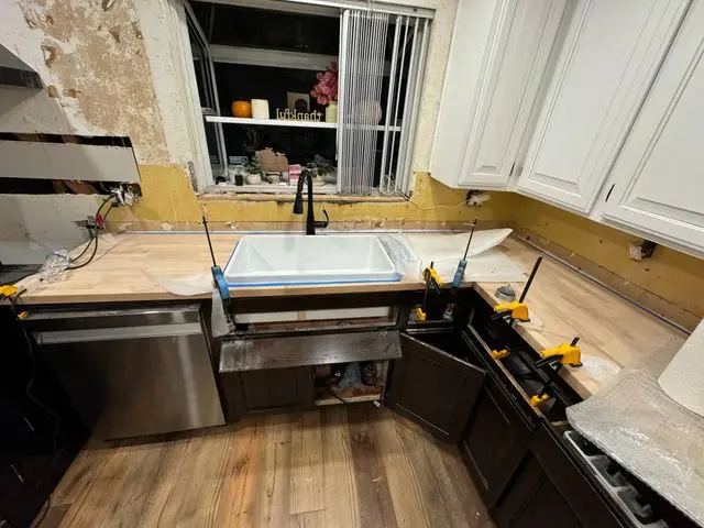 Kitchen cabinet run mid install, clamps holding the face frames beside a new sink. Work by Construction Hub in Los Angeles.