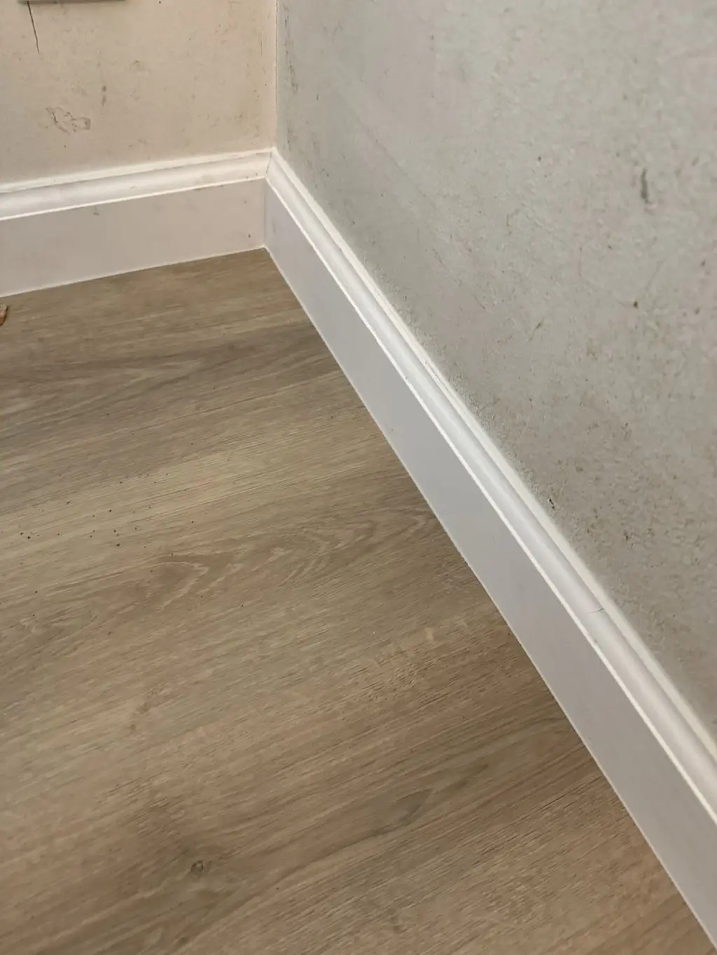 White baseboard trim installed along new vinyl plank floor. Work by Construction Hub in Los Angeles.