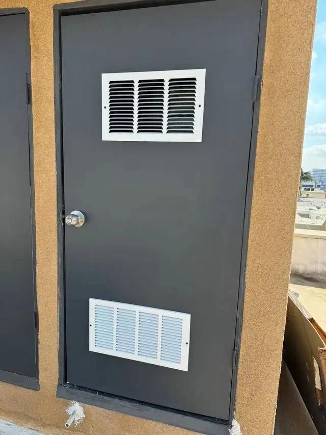 Gray metal utility door with two white louvered vents. Work by Construction Hub in Los Angeles.