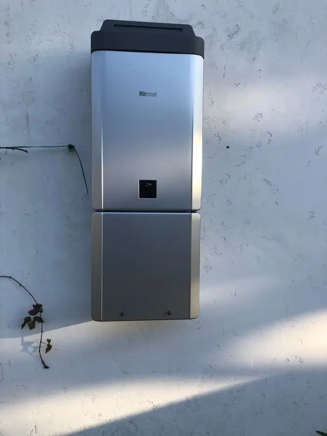 Tankless water heater mounted on white exterior stucco wall. Work by Construction Hub in Los Angeles.
