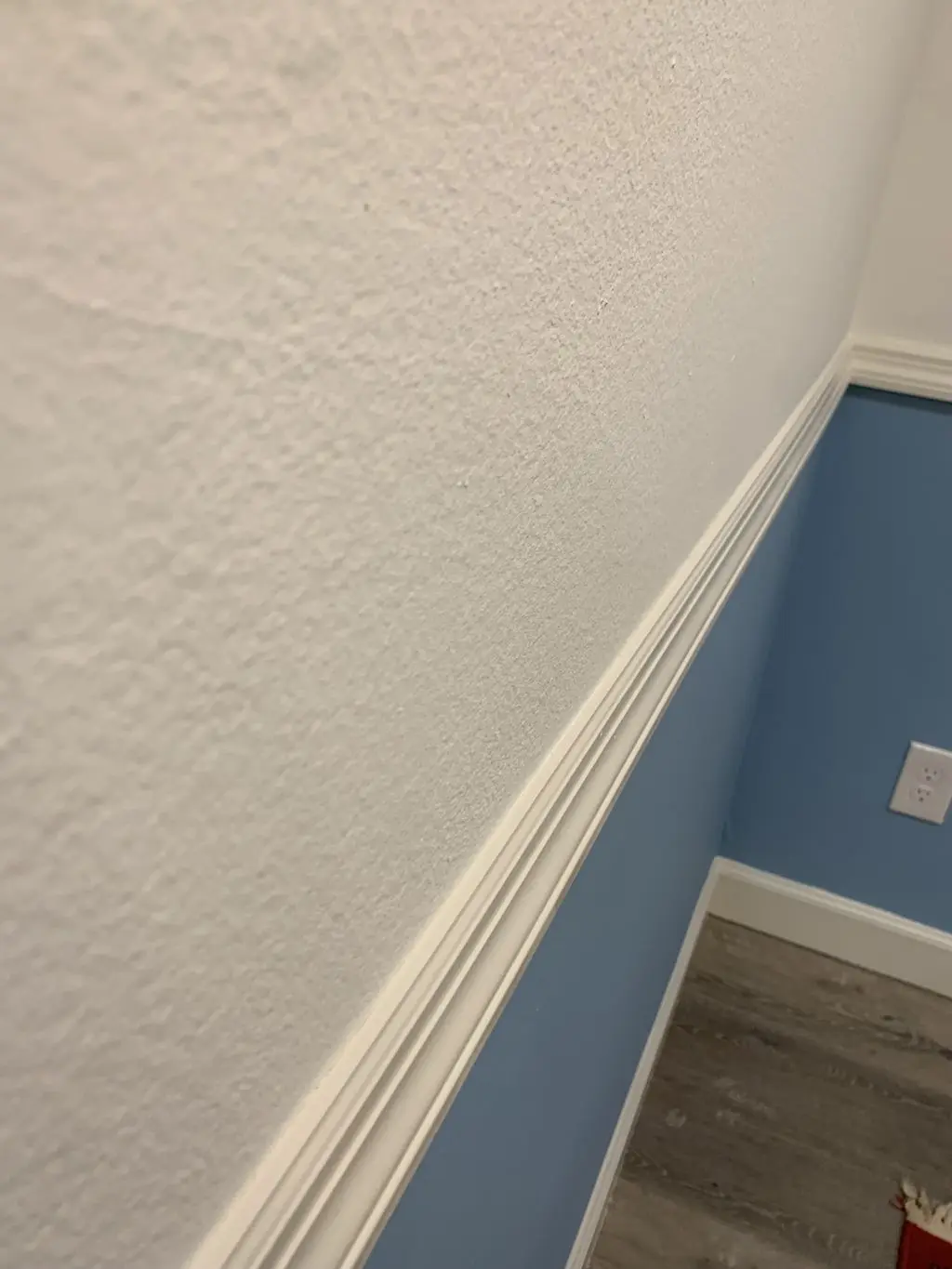 Close up of white chair rail molding dividing white and blue walls. Work by Construction Hub in Los Angeles.