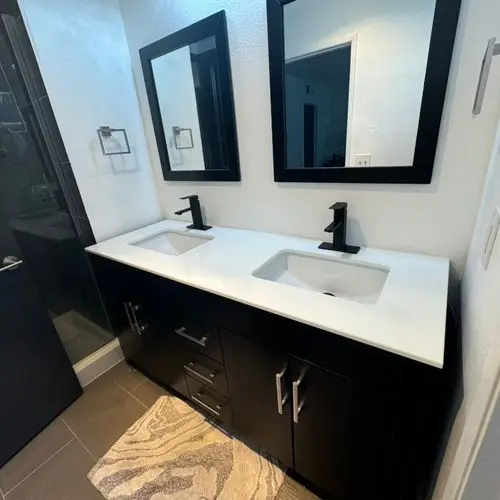 Double vanity with black cabinets, quartz top and framed mirrors. Work by Construction Hub in Los Angeles.