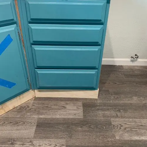 Teal cabinet base with new toe kick on wood-look floor. Work by Construction Hub in Los Angeles.