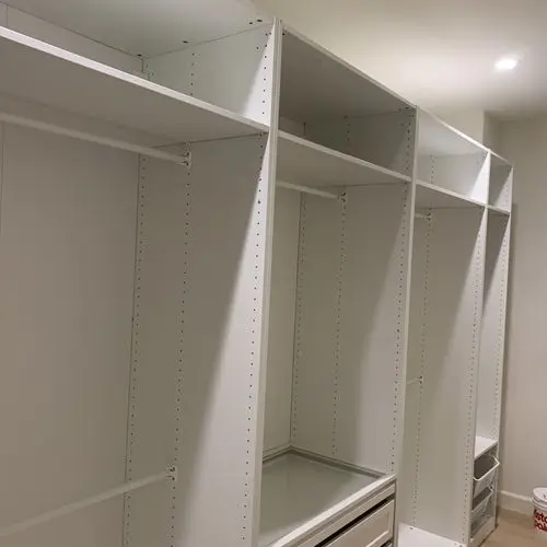 Row of white closet towers with adjustable shelves and hanging rods. Work by Construction Hub in Los Angeles.