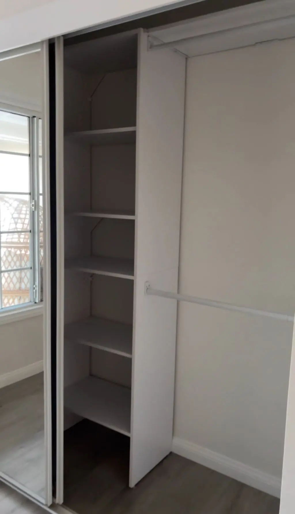 Closet shelf tower and rods behind sliding mirrored doors. Work by Construction Hub in Los Angeles.