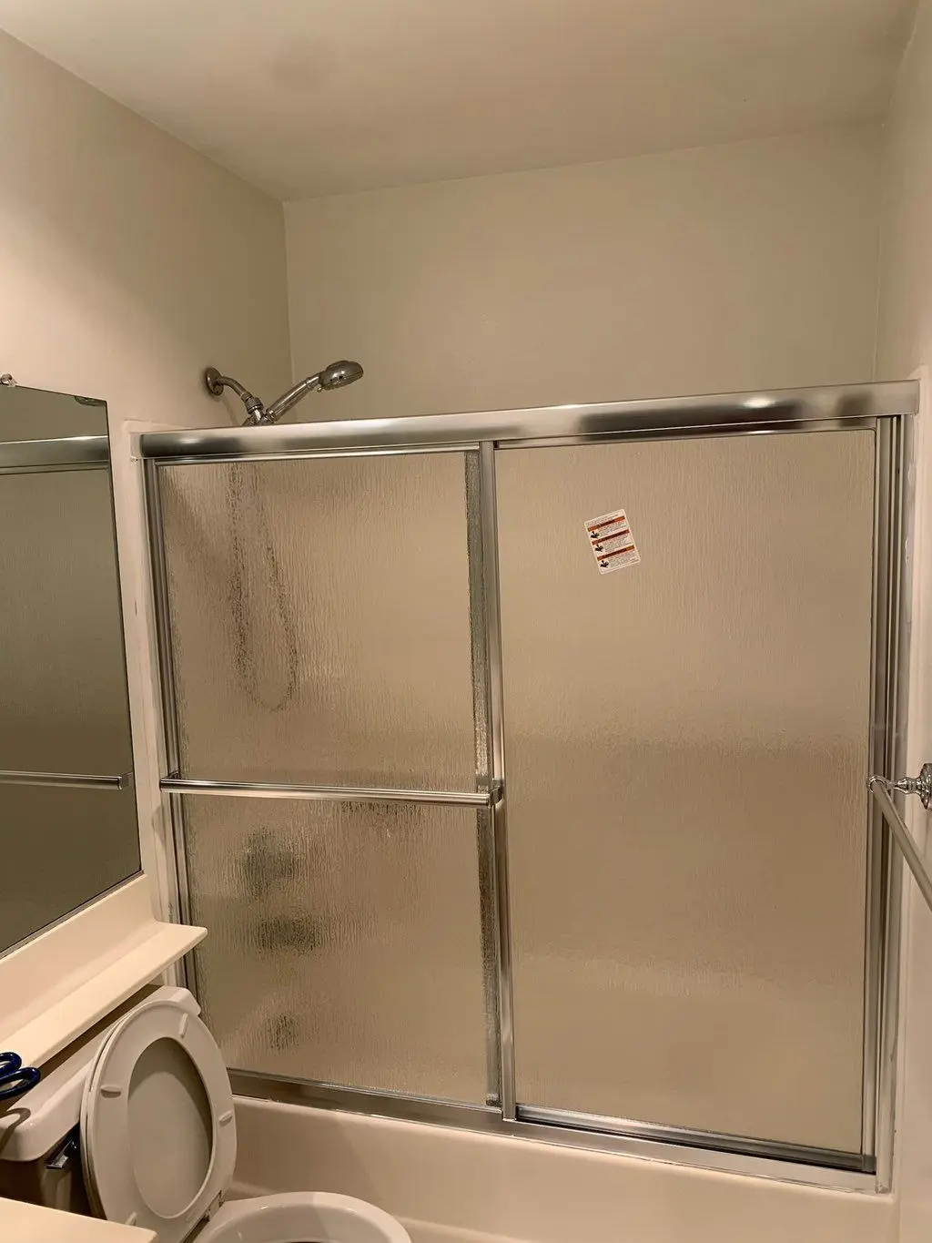 New chrome framed sliding shower doors with textured glass over tub. Work by Construction Hub in Los Angeles.