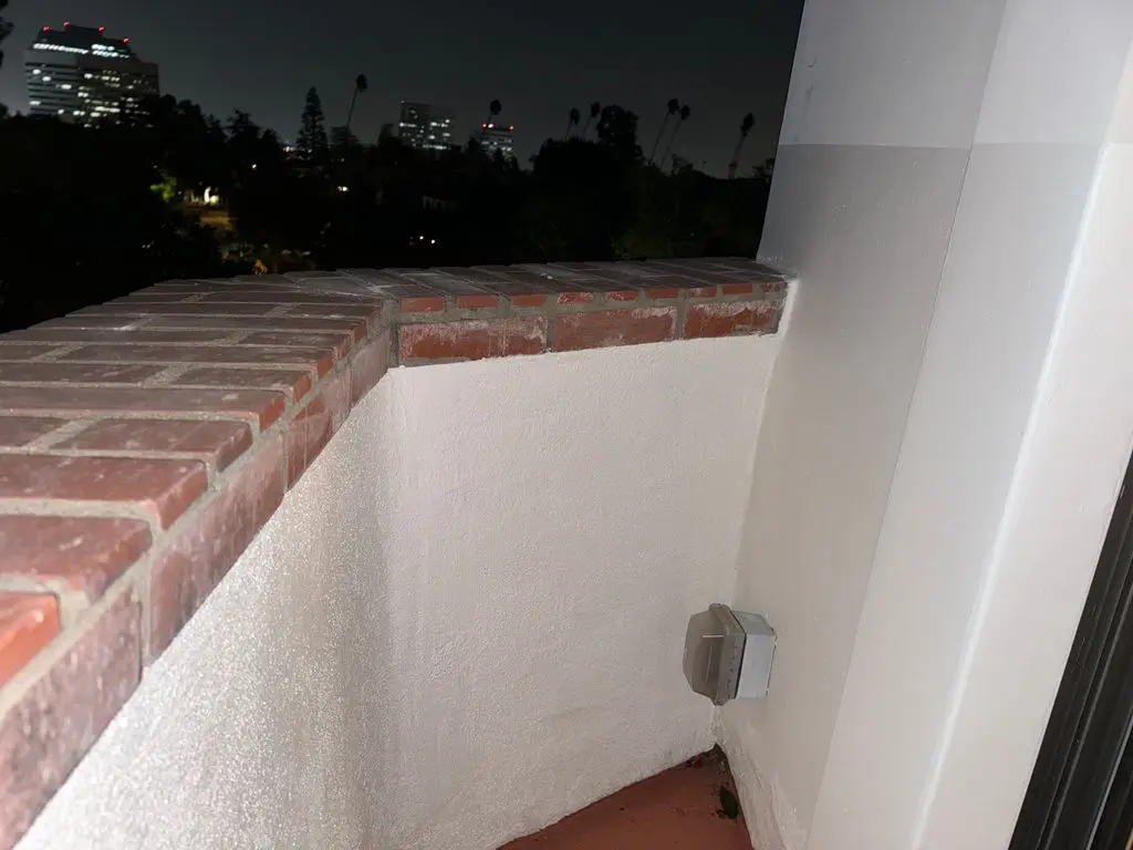 Freshly painted white stucco balcony wall under brick cap. Work by Construction Hub in Los Angeles.