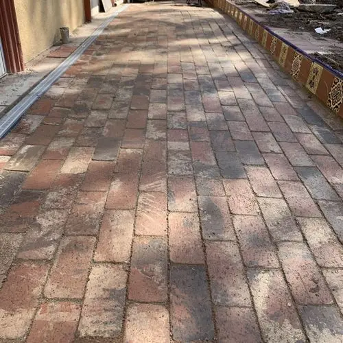 Brick paver walkway with channel drain and decorative tile border. Work by Construction Hub in Los Angeles.