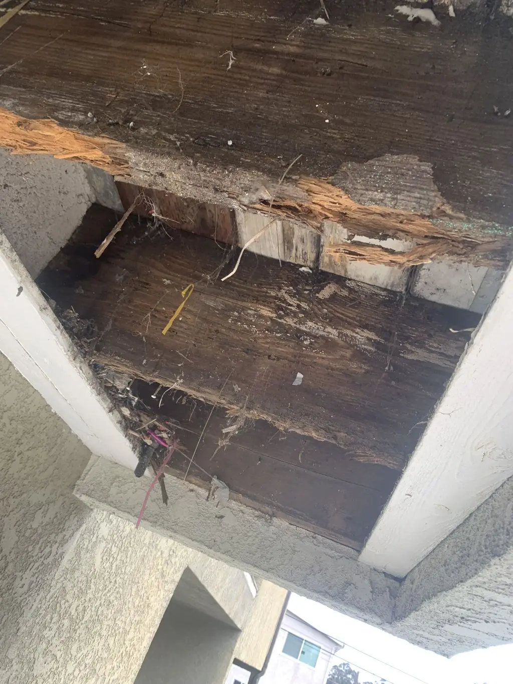 Close-up of rotted soffit boards and decayed wood beam. Work by Construction Hub in Los Angeles.