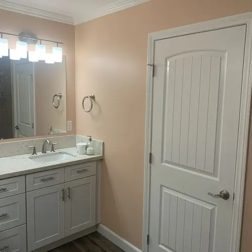 Bathroom with peach painted walls, white vanity, mirror and door. Work by Construction Hub in Los Angeles.