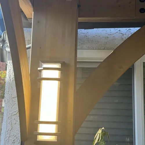 Wall sconce mounted and lit on a cedar pavilion post. Work by Construction Hub in Los Angeles.