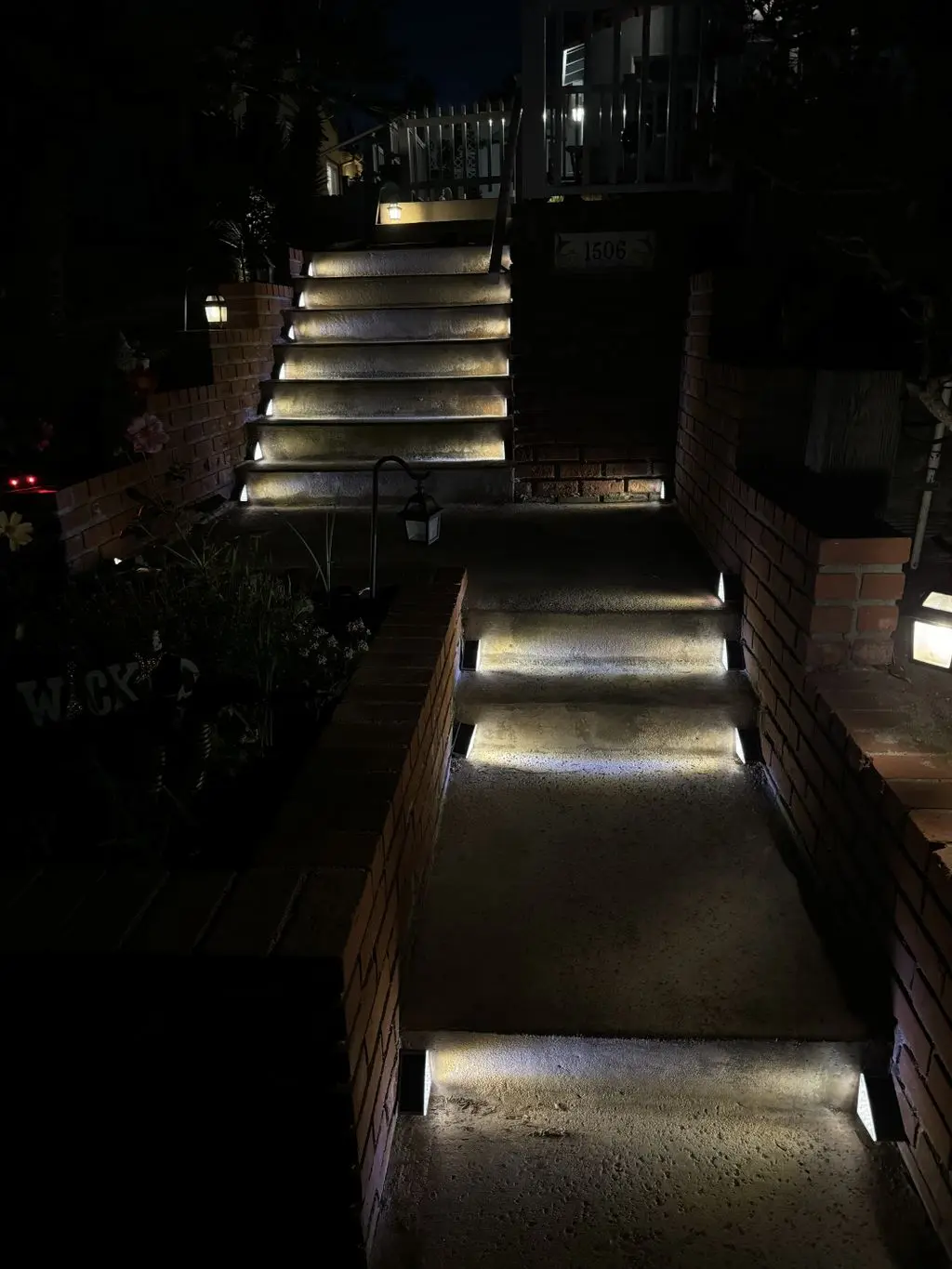 Low-voltage step lights lighting brick entry stairs at night. Work by Construction Hub in Los Angeles.