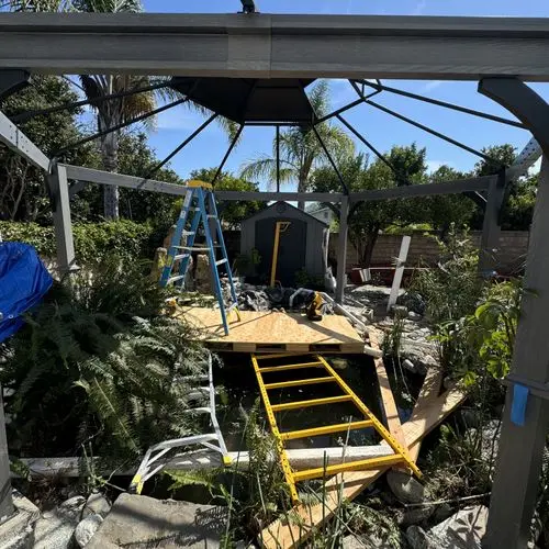 Gazebo frame partly built with ladder and platform over pond. Work by Construction Hub in Los Angeles.