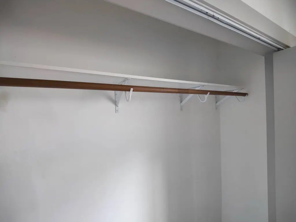 White closet shelf and wood rod on metal brackets. Work by Construction Hub in Los Angeles.