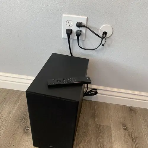 Subwoofer beside an outlet and cable pass through wall plate. Work by Construction Hub in Los Angeles.
