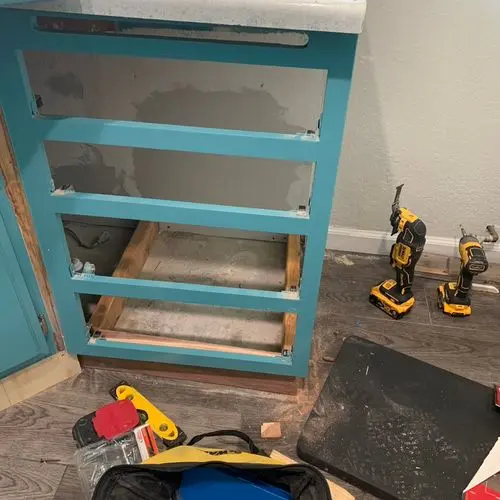Teal cabinet with drawers removed and slides exposed, tools nearby. Work by Construction Hub in Los Angeles.