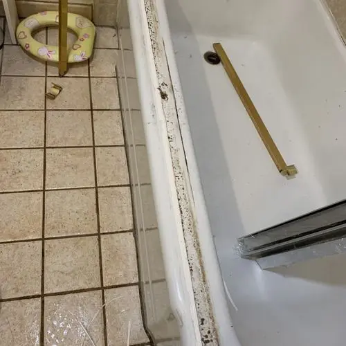 Old shower door track removed and laid inside a stained tub. Work by Construction Hub in Los Angeles.