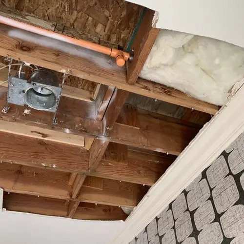 Ceiling cavity exposed with insulation, copper pipe and light housing. Before the work, by Construction Hub in Los Angeles.
