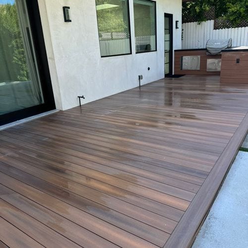 Finished composite deck patio beside white stucco house. Work by Construction Hub in Los Angeles.