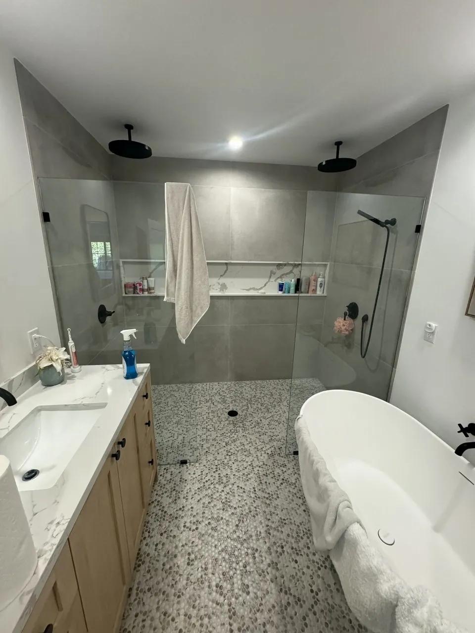 Bathroom with glass-enclosed shower, freestanding tub, quartz vanity and pebble tile floor