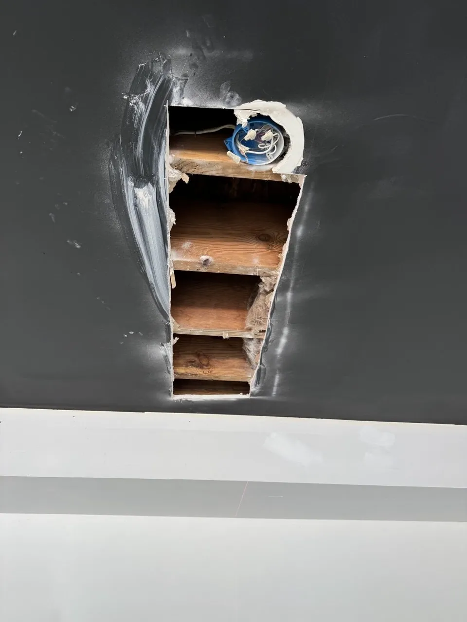 Ceiling opened around a recessed light showing framing before the drywall patch. Work by Construction Hub in Los Angeles.
