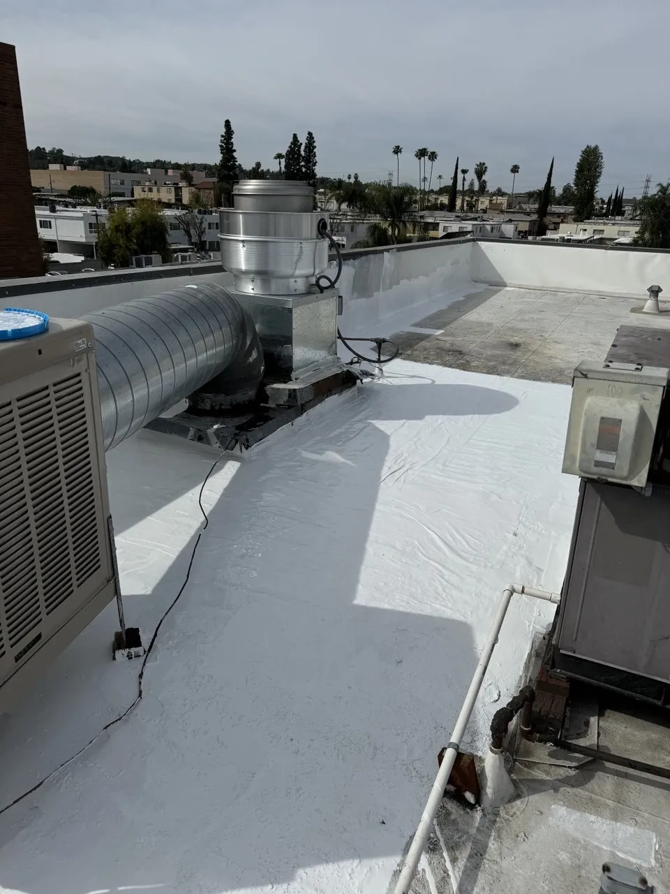Flat roof recoated with white membrane around rooftop equipment